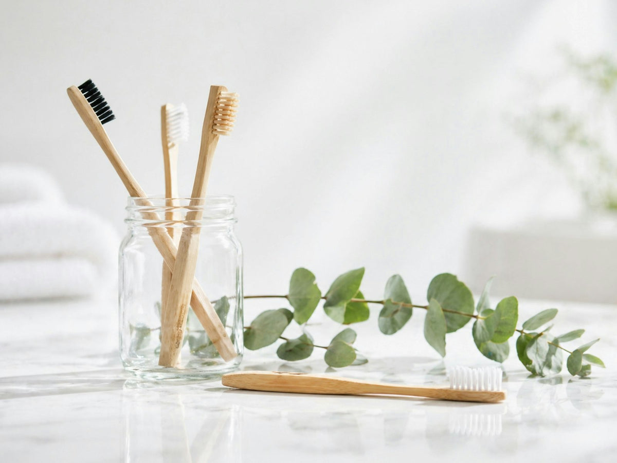 Bamboo toothbrushes in a glass jar with eucalyptus leaves